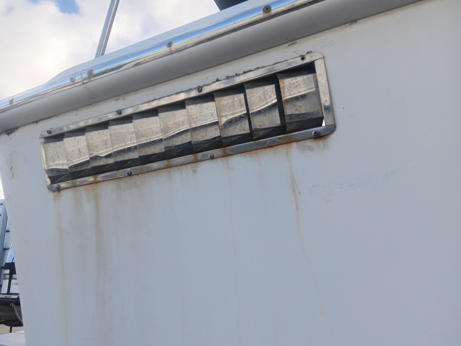 Corroded stainless steel hull vent before restoration, showing rust staining and pitting